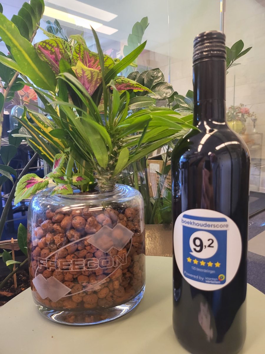 Fles met de boekhouderscore-sticker naast een glazen pot met het Freecon-logo op ons kantoor